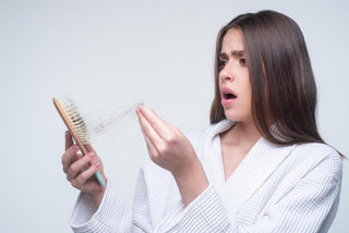 Woman looking at her hair brush and hair loss